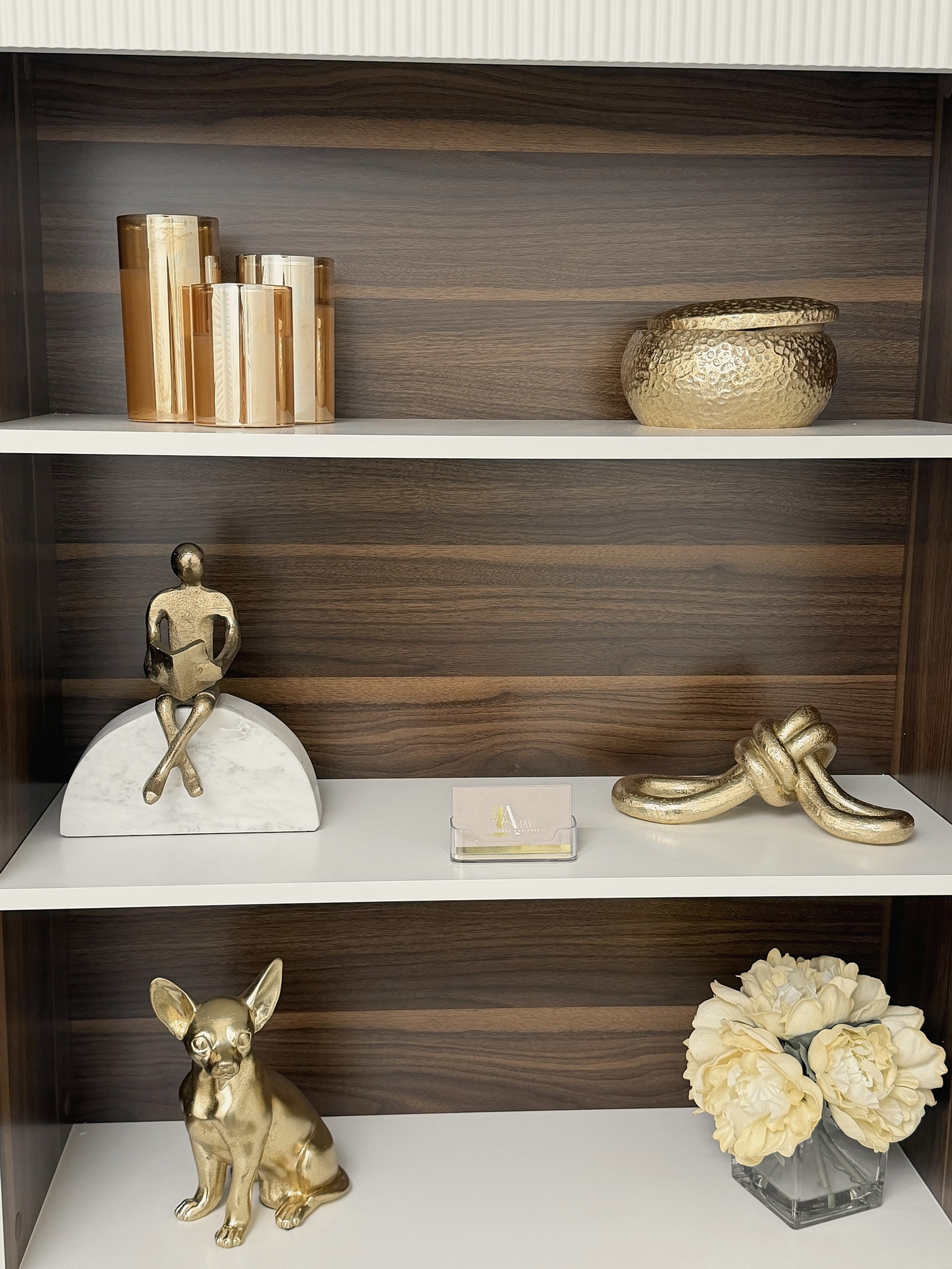 Gold decorative objects and AMay Legal Doc Prep branding styled on the office bookshelf